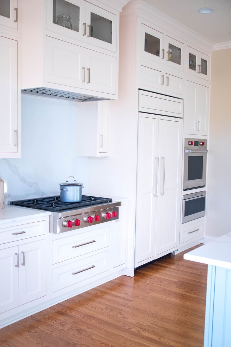White cabinets, modern stovetop, red accents, and hardwood floors
