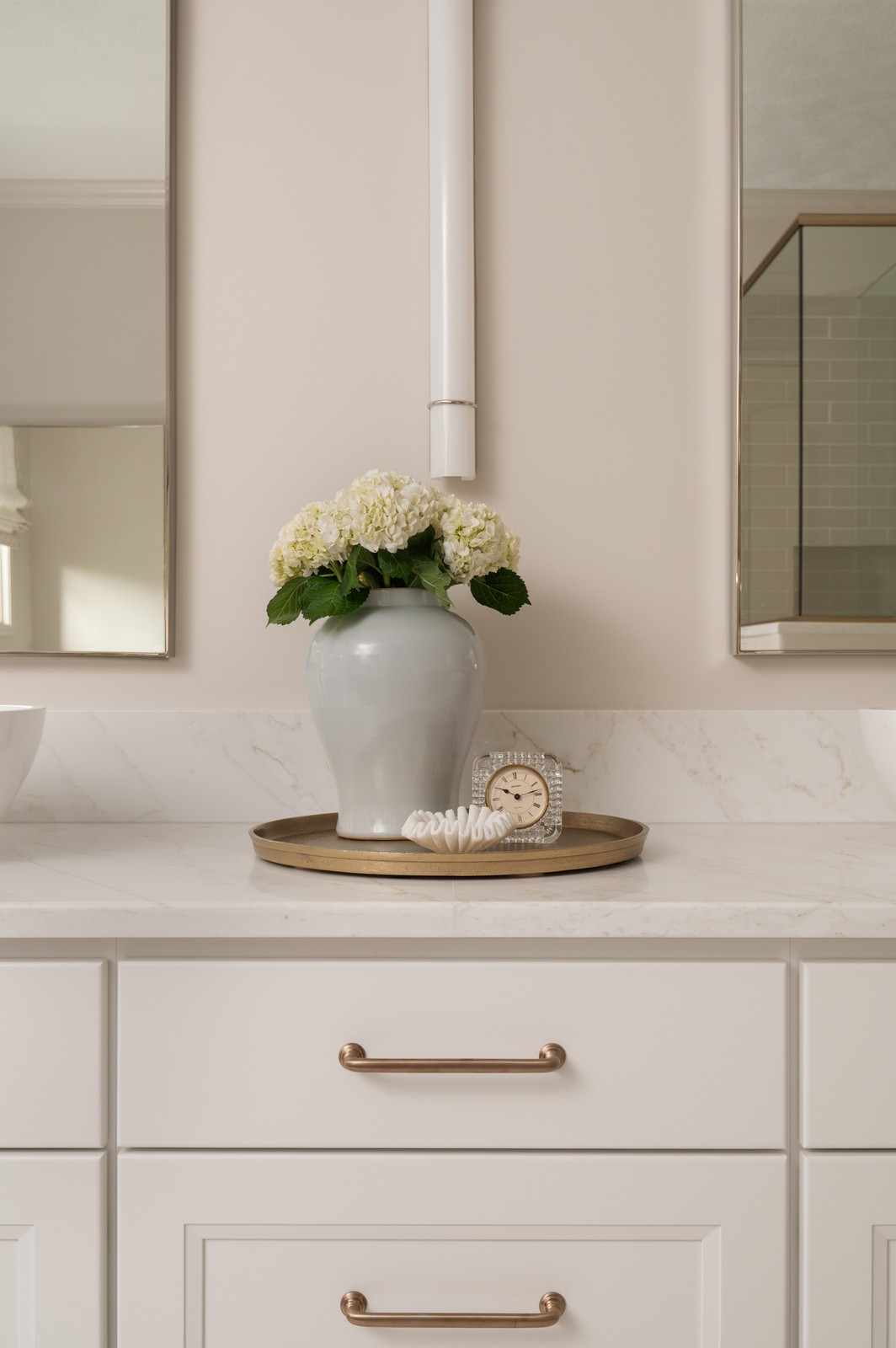 Bathroom vanity countertop detail with brass tray, vase, and clock in Michiana primary bathroom, designed by Peacock and Co