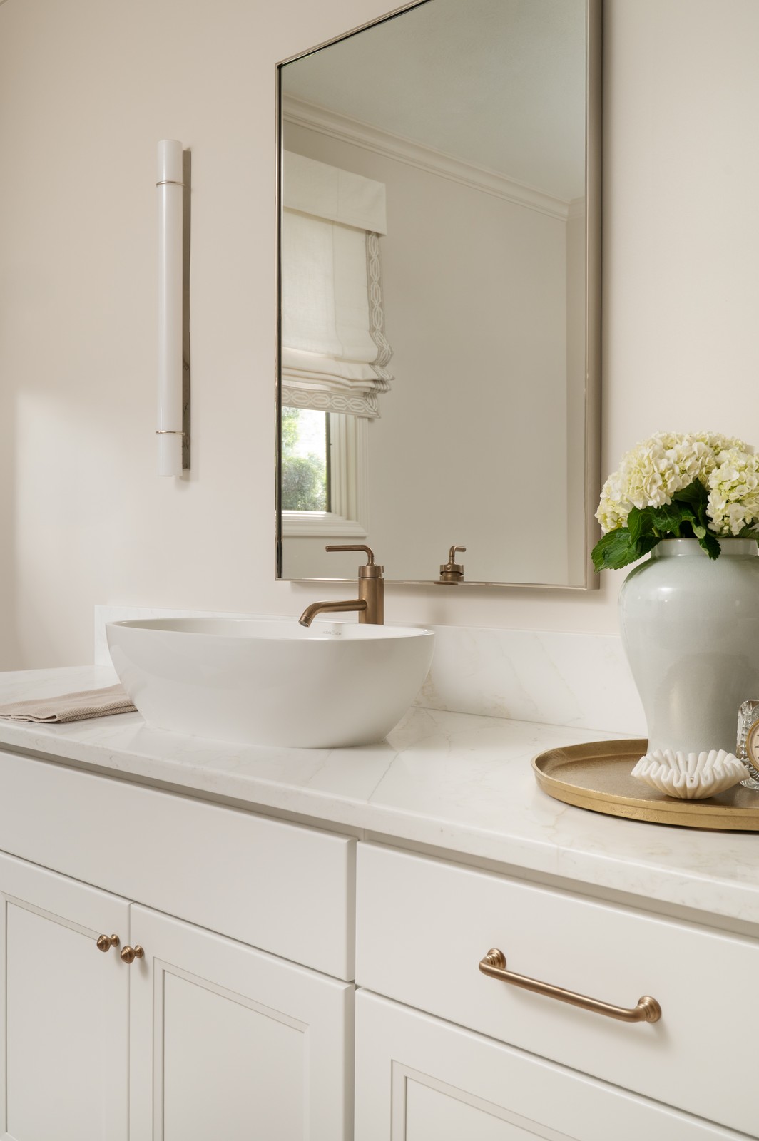Close up of vessel sink and brass faucet with hydrangea arrangement in Michiana primary bathroom