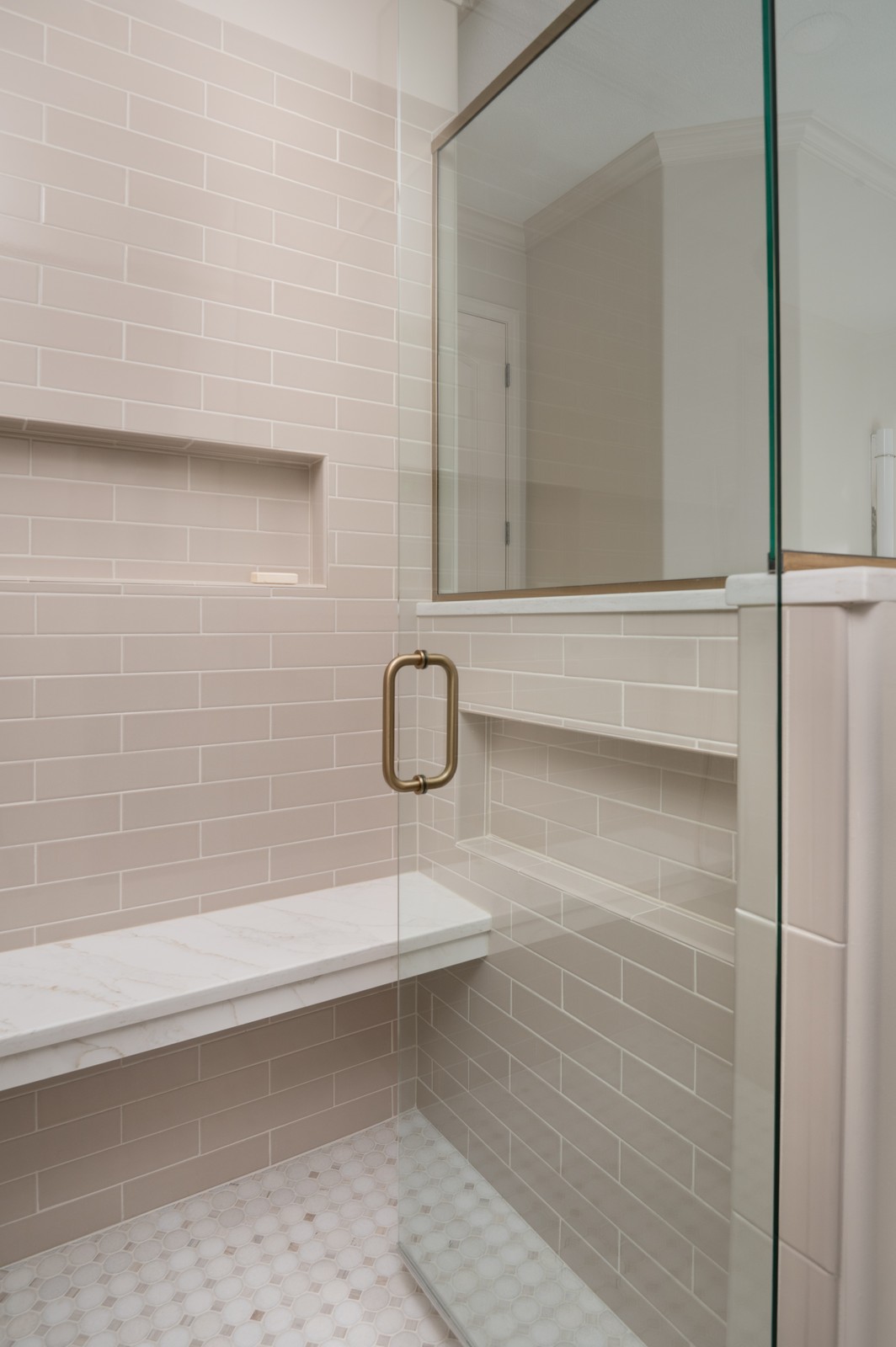 Corner shower enclosure with brass hardware and marble bench in Michiana primary bathroom remodel