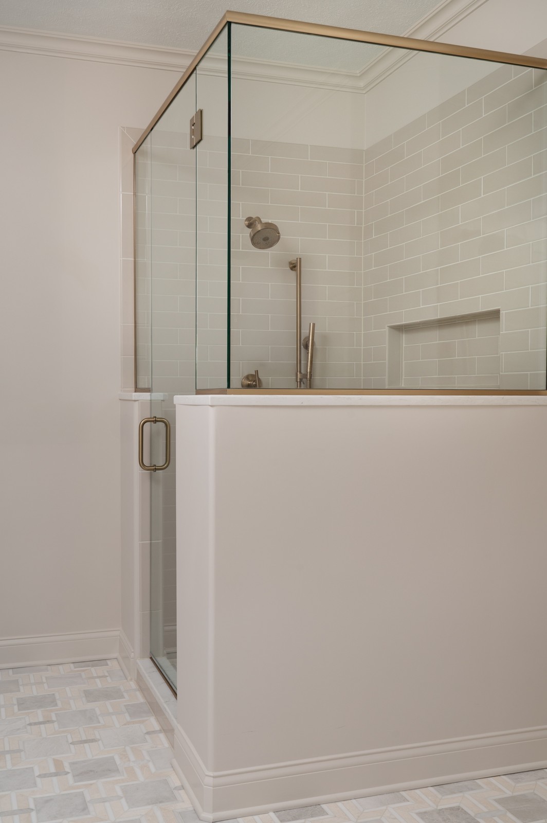 Corner view of glass shower enclosure with brass trim in Michiana primary bathroom remodel
