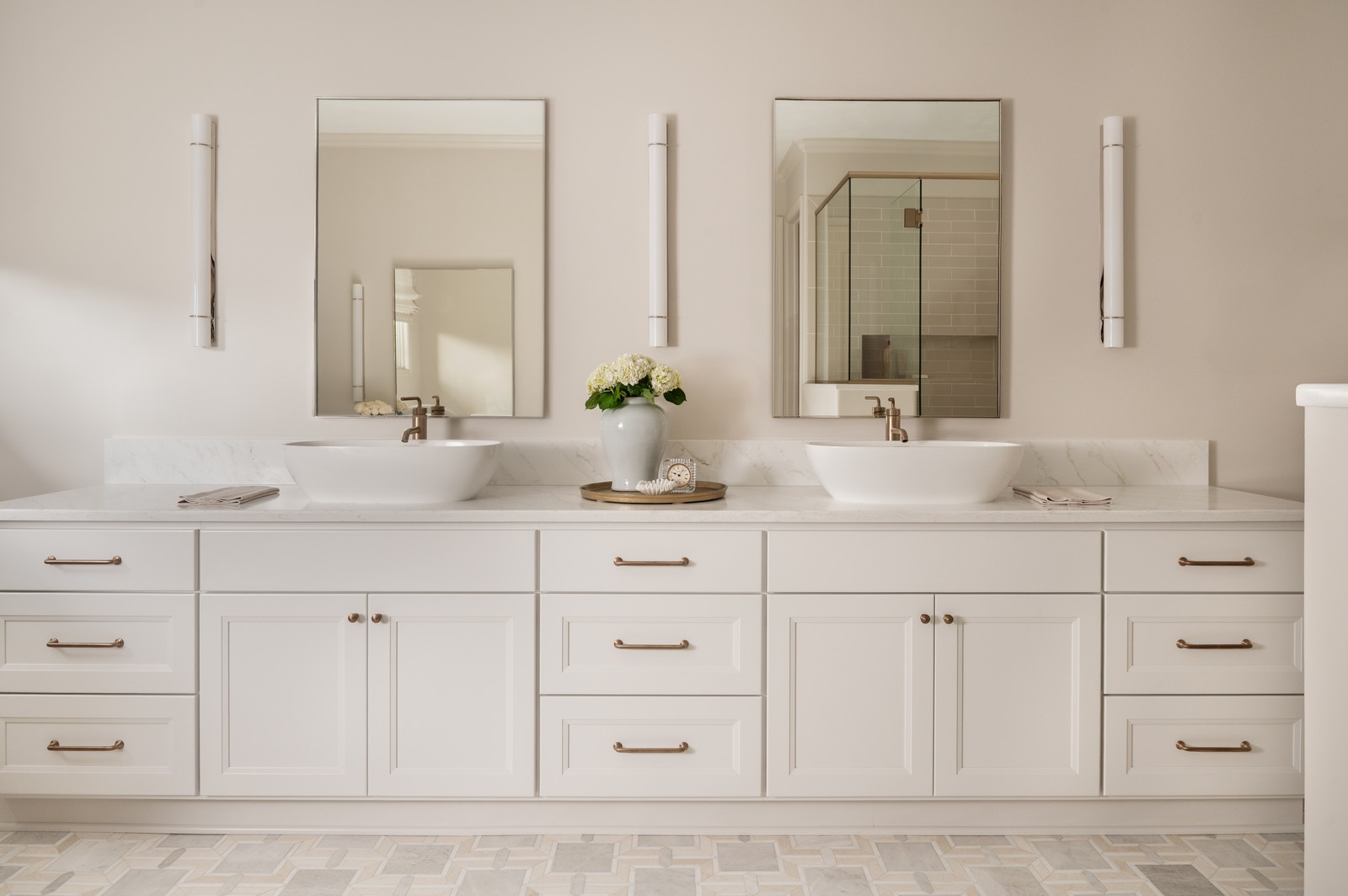 Double vanity with two vessel sinks and brass wall sconces in Michiana primary bathroom, designed by Peacock and Co