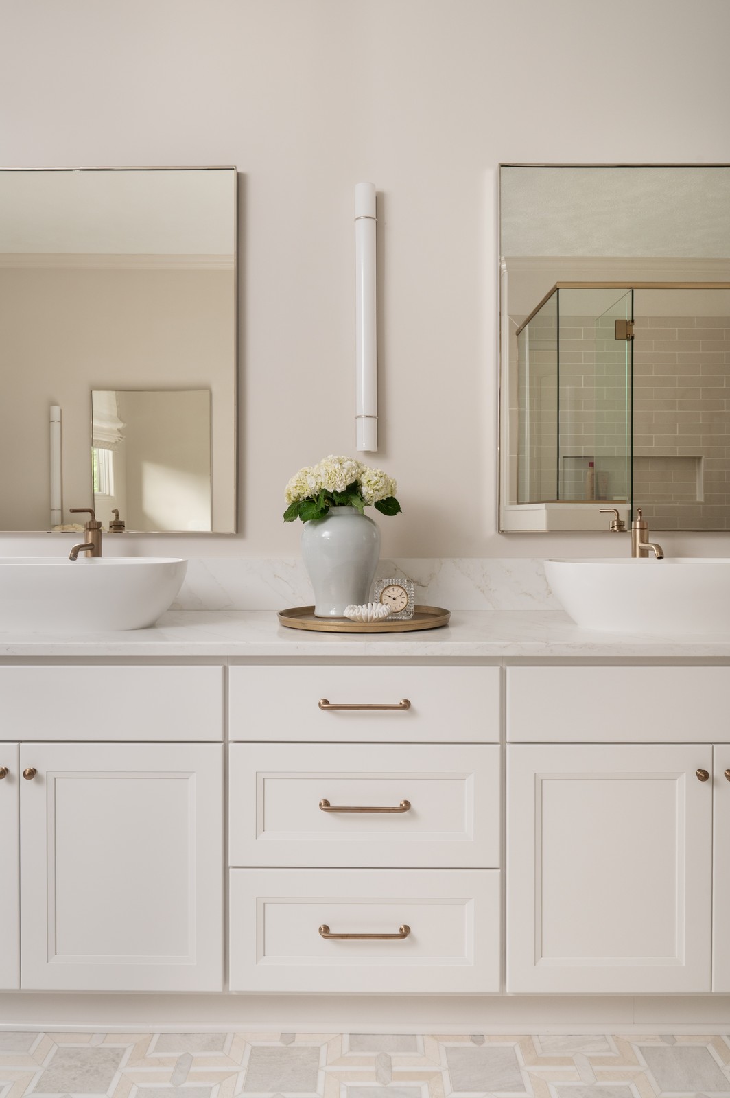 Double vanity with white vessel sinks, brass hardware, and hydrangea centerpiece in Michiana primary bathroom remodel