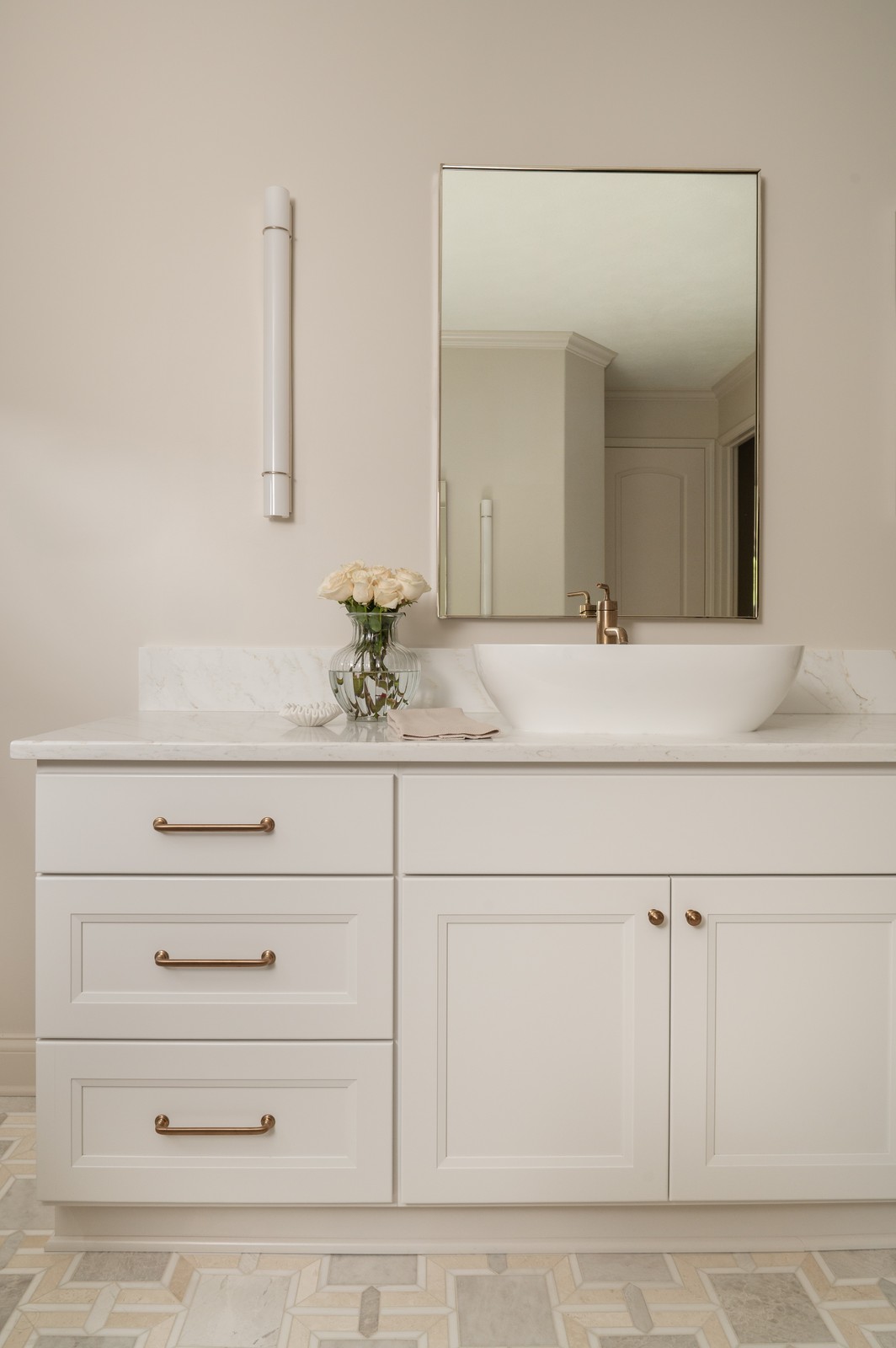 Single vanity with white vessel sink, brass faucet, and framed mirror in Michiana primary bathroom