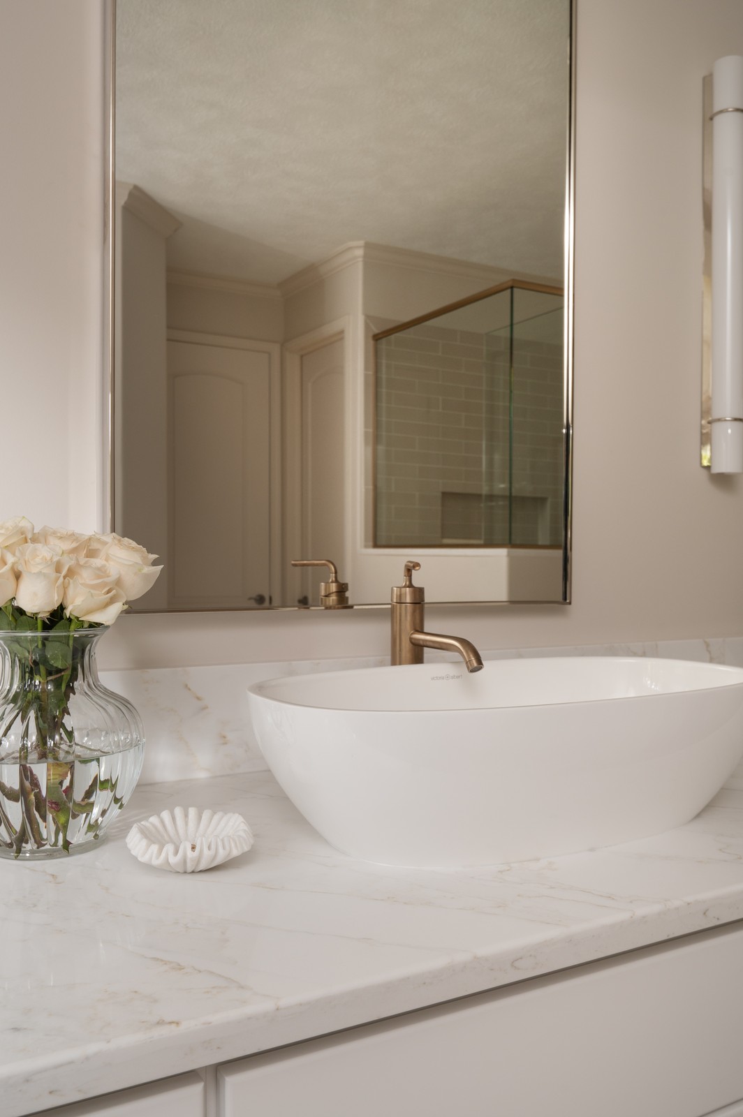 White vessel sink with brass faucet and mirror reflecting walk in shower in Michiana primary bathroom