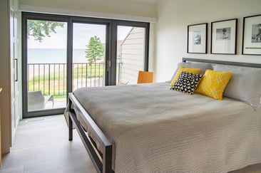 Bright bedroom with lake-view sliding doors, neutral bedding, and modern decor in South Haven, MI