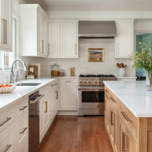 Bright white kitchen with wood island, brass hardware, stainless range, large island, and warm wood floors (1) (1)
