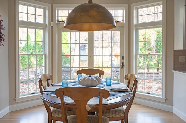 Cozy breakfast nook in Indiana with round wood table, large windows, and autumn views outside