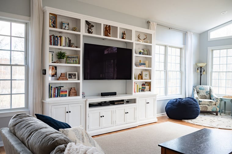 Custom entertainment system with open shelving in sunroom addition by Peacock & Company