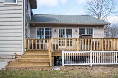 Deck and sunroom addition exterior with wood steps and railing by Peacock and Company