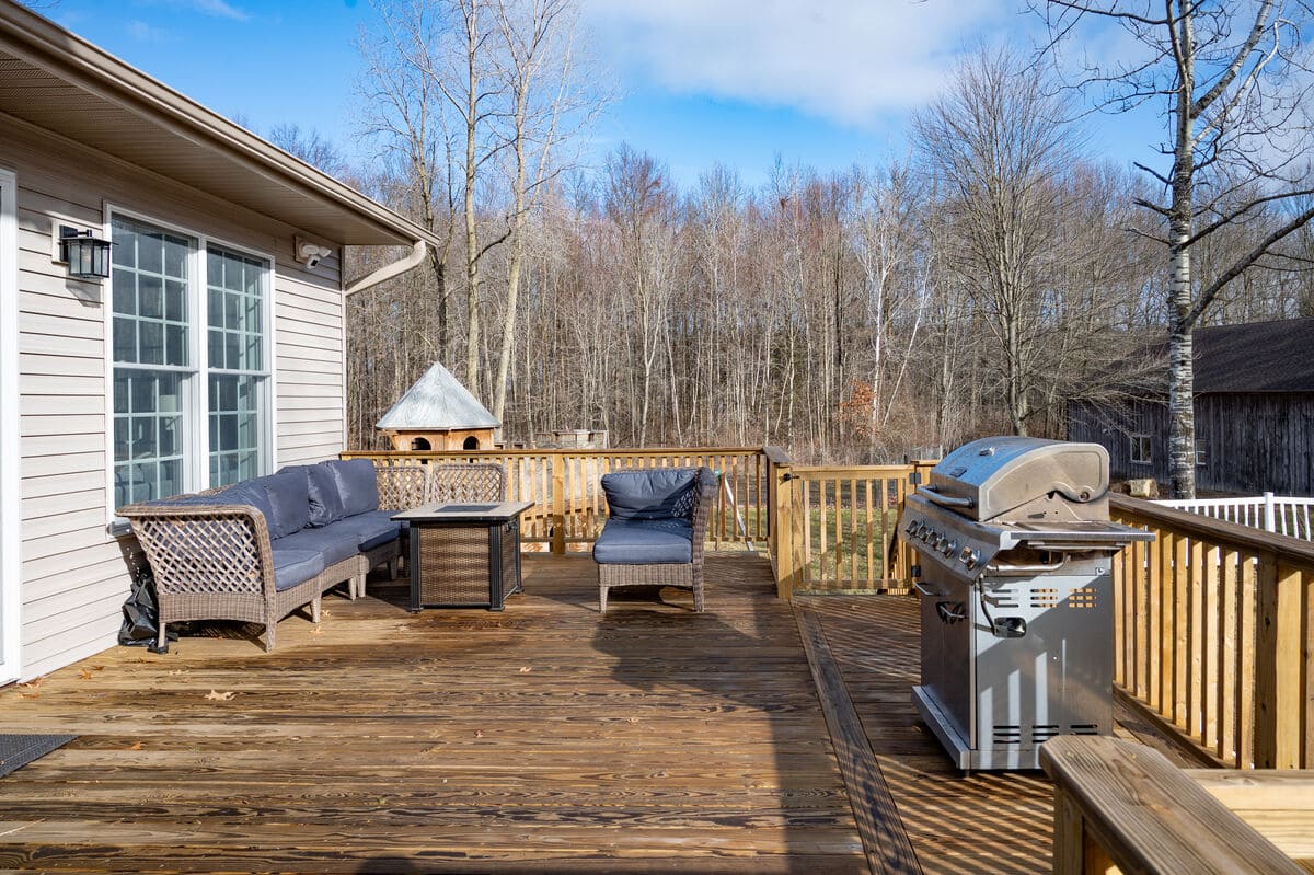 Deck on sunny day in South Bend, IN with grill and fire pit by Peacock and Company