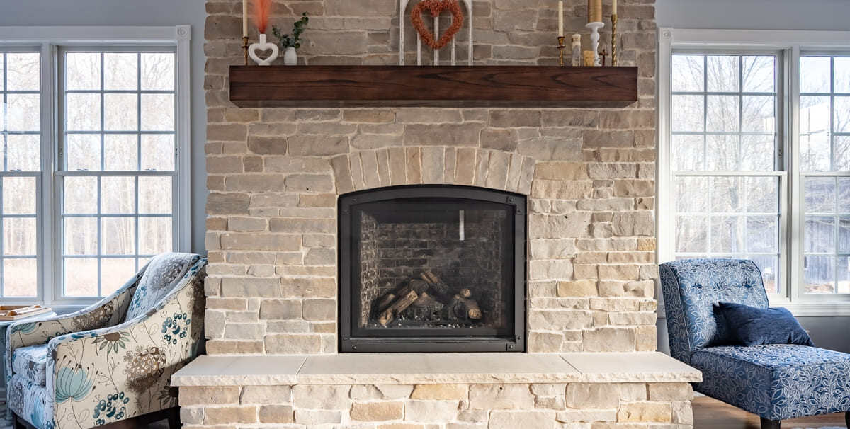 Floor-to-ceiling stone fireplace in sunroom addition by Peacock & Company