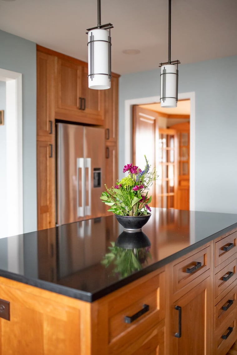 Craftsman style kitchen island with natural wood and dark countertop and pendant lights By Peacock & Co in South Bend