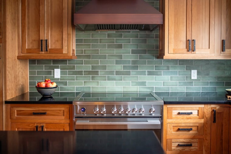 View of stove and bronze range hood in kitchen remodel by Peacock & Co in South Bend