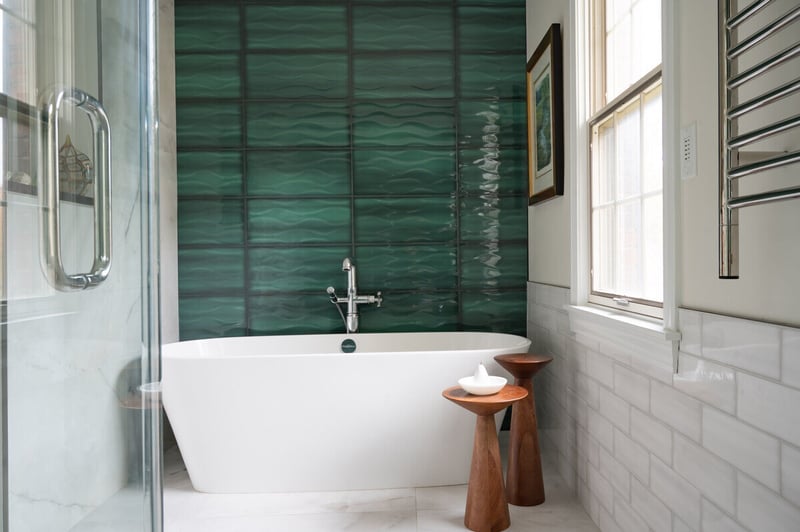 Freestanding tub with green tile accent wall in South Bend, IN bathroom remodel by Peacock & Company