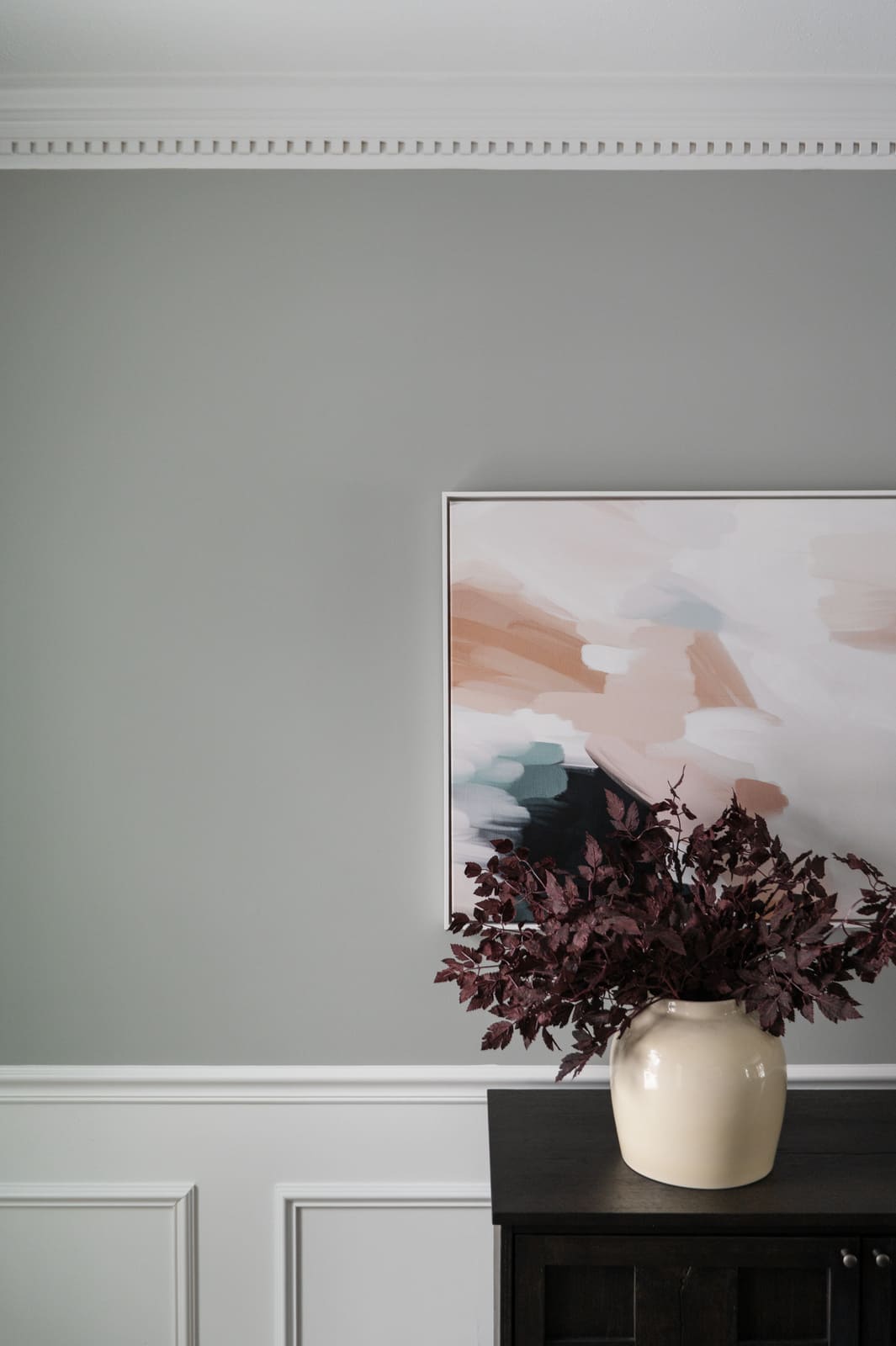 Abstract artwork and vase on a dark sideboard against gray walls and white trim in a Granger, IN dining room