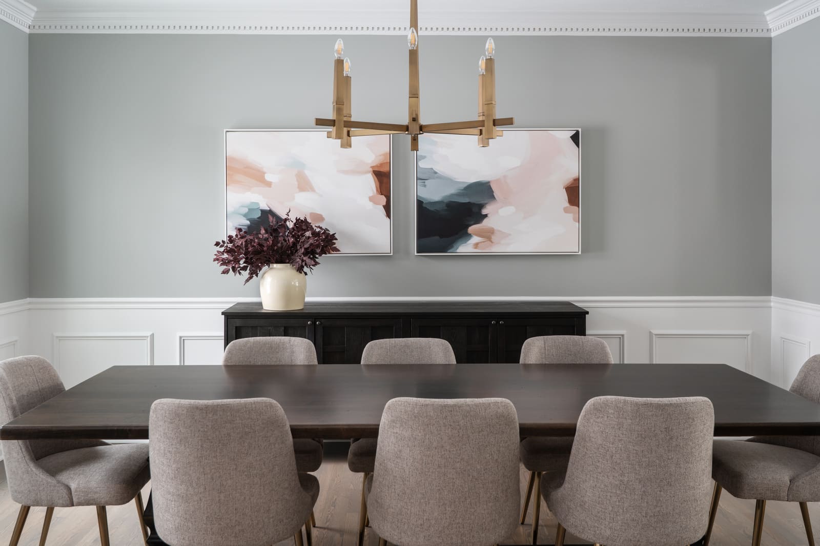 Formal dining room in Granger, IN with brass chandelier, dark wood table, upholstered chairs, and abstract wall art