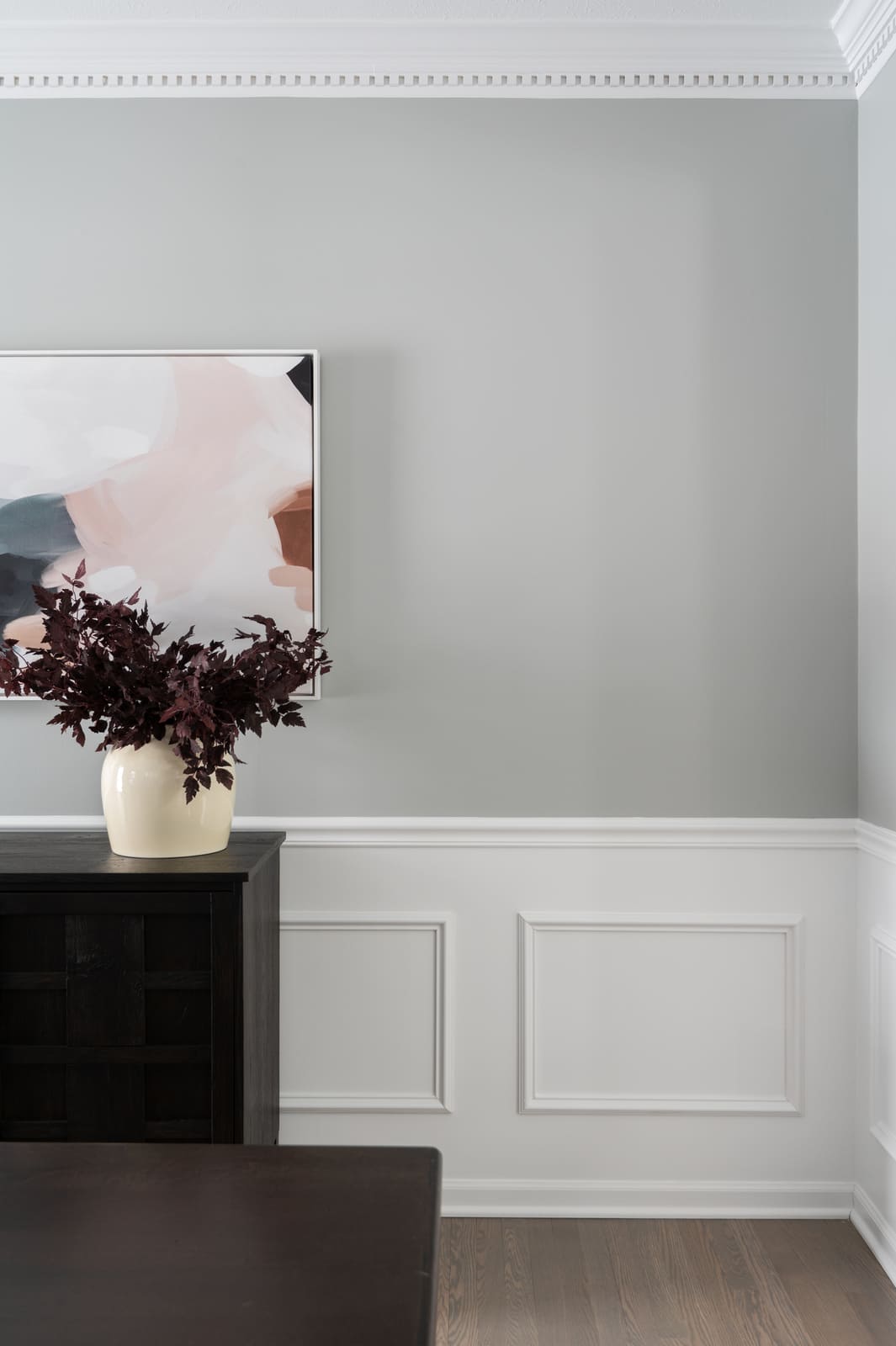 Granger, IN dining room wall with white wainscoting, crown molding, sideboard, and abstract artwork