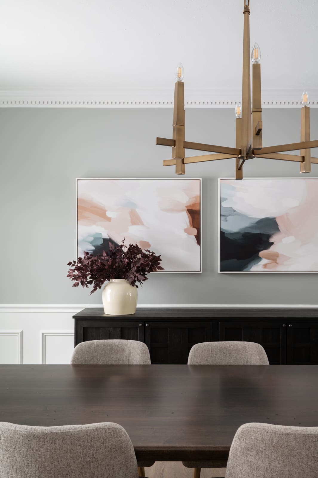 Granger, IN dining room with brass chandelier, abstract wall art, dark wood table, and upholstered chairs