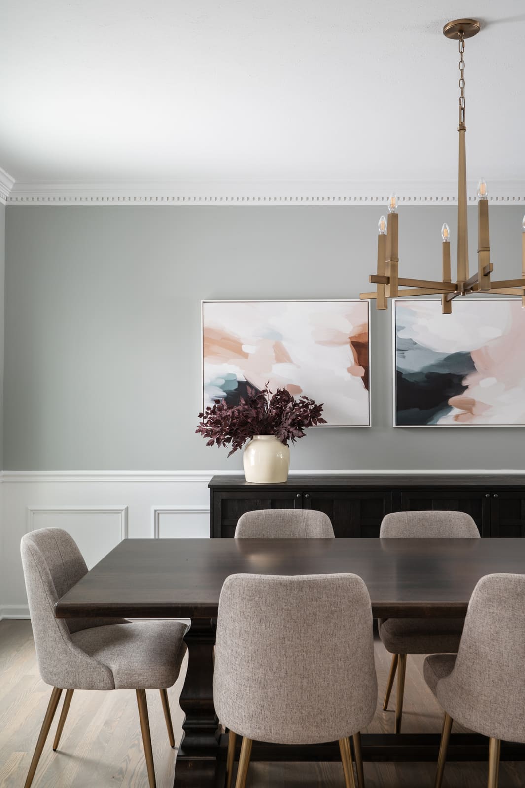 Granger, IN dining room with brass chandelier, dark wood table, upholstered chairs, and abstract wall art