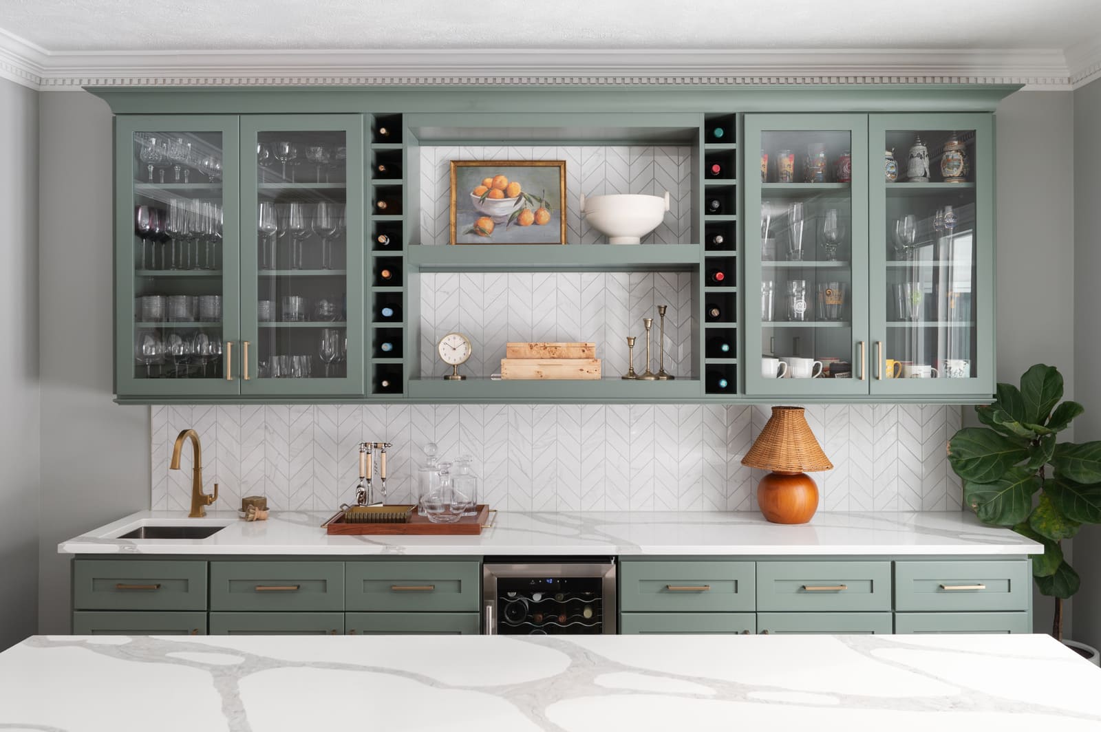 Granger, IN kitchen bar with sage green cabinet, wood shelves, framed art, pottery, and brass candlesticks