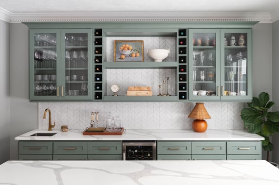 Granger, IN kitchen bar with sage green cabinet, wood shelves, framed art, pottery, and brass candlesticks