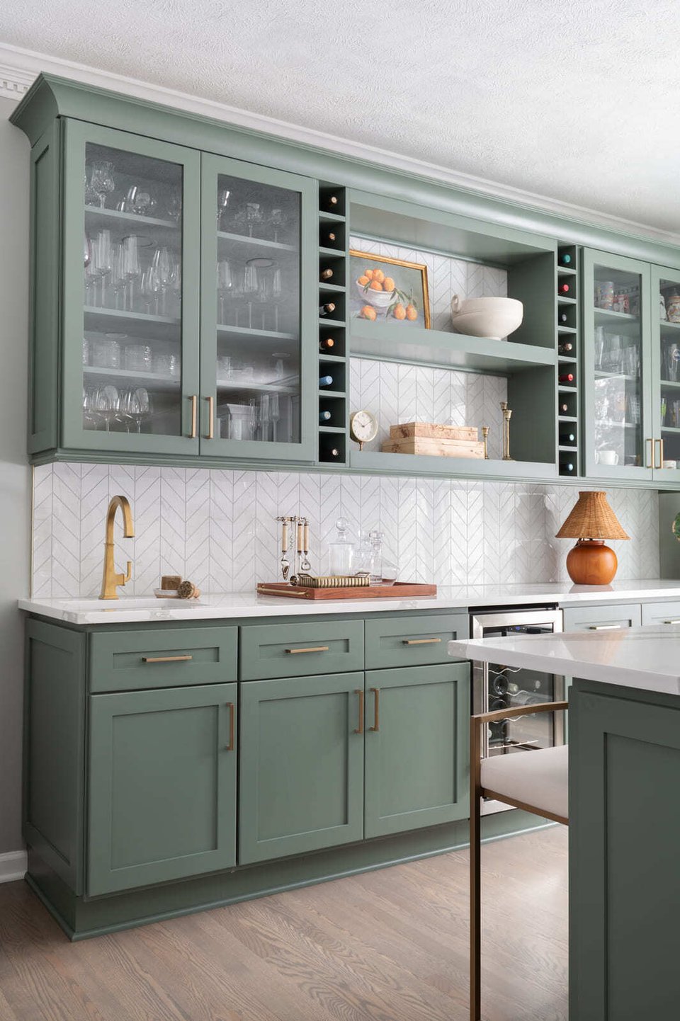 Granger, IN kitchen with sage green glass-front cabinets, brass hardware, white tile backsplash, and bar sink