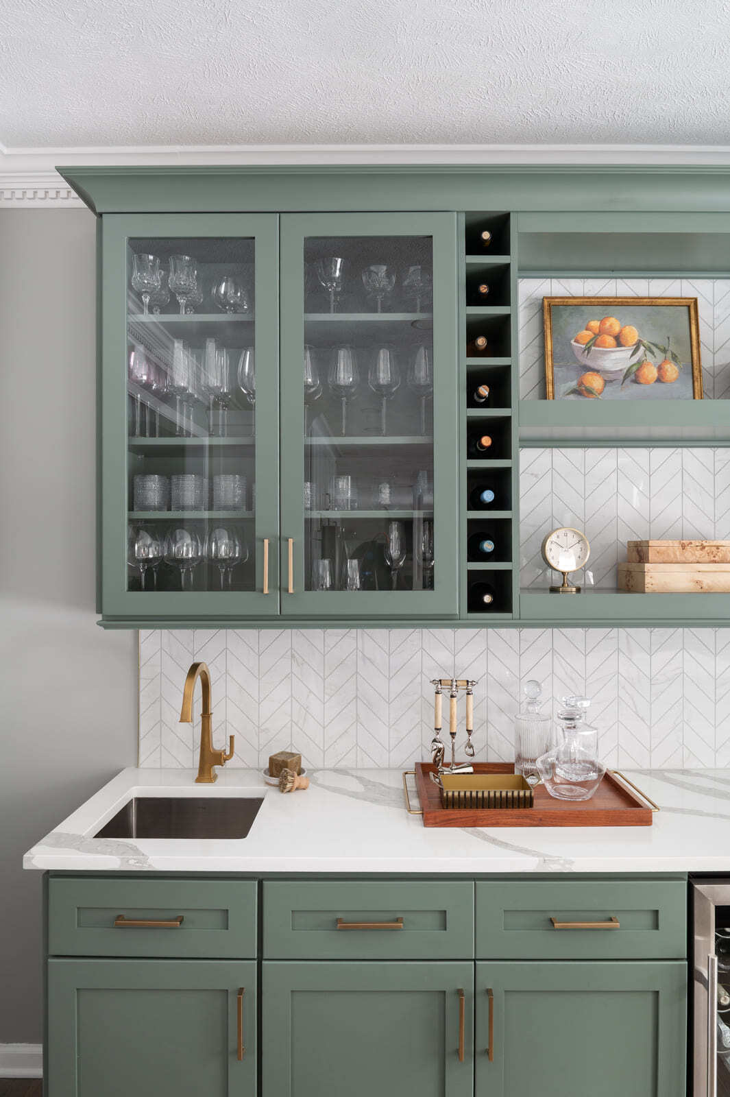 Granger, IN kitchen with sage green upper cabinets, brass faucet, white chevron backsplash, and bar sink