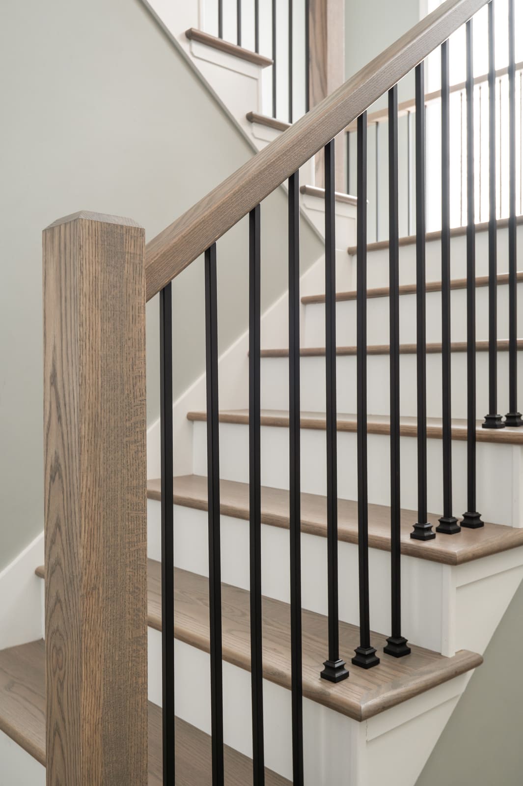 Granger, IN staircase with light wood handrail, black balusters, and white risers in a bright entry hall
