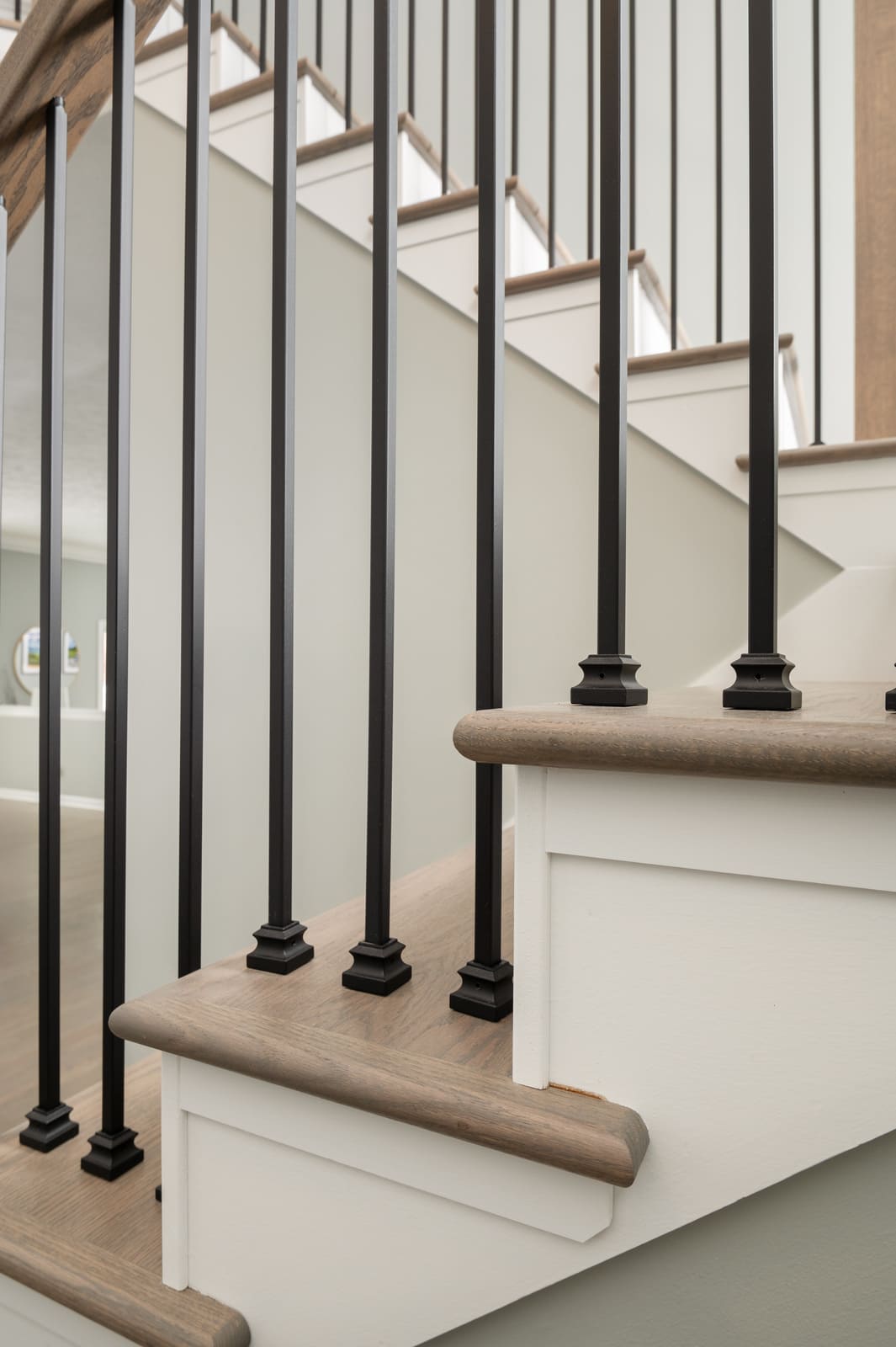 Stair detail in Granger, IN with light wood treads, black balusters, and white stair trim