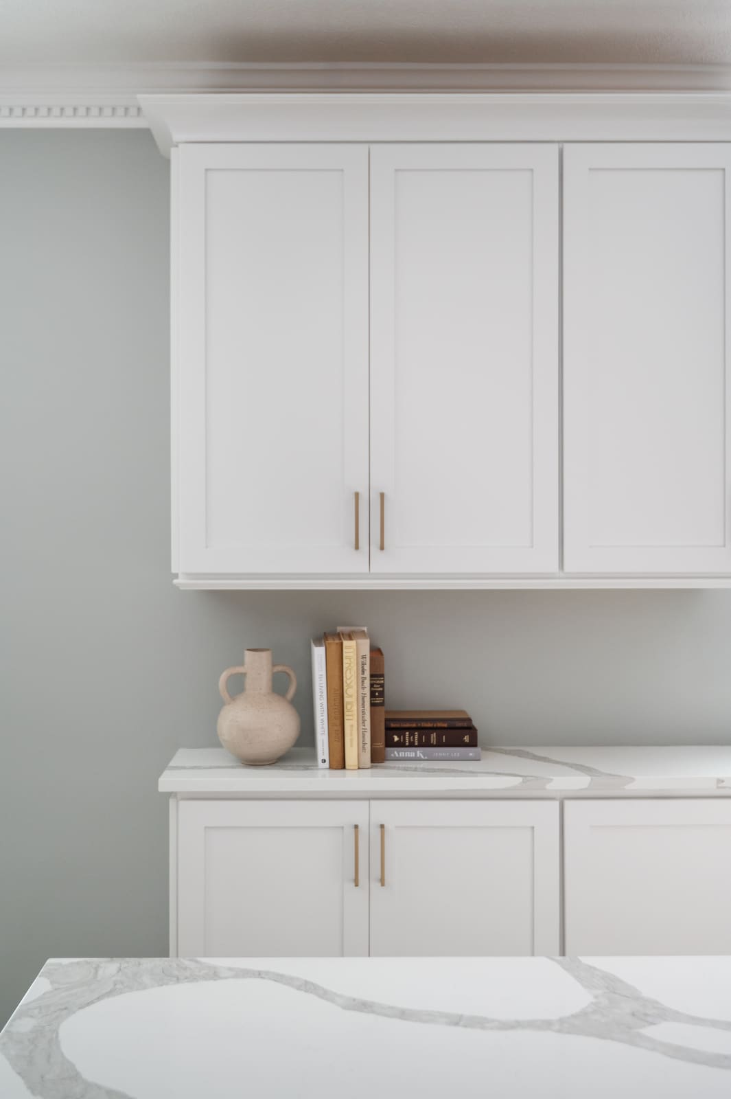 White kitchen cabinets and counter in Granger, IN with brass pulls, books, and quartz countertop