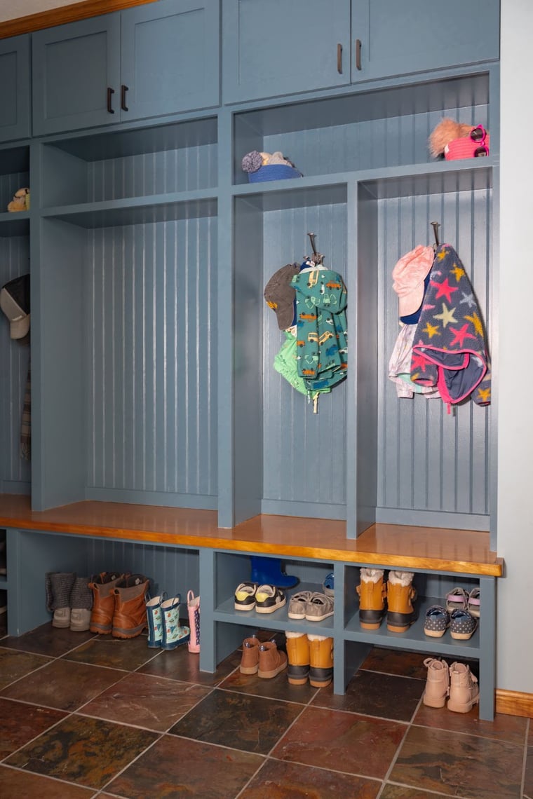 Built-in blue mudroom lockers with wood bench and tile floor for shoes and coats located in Indiana