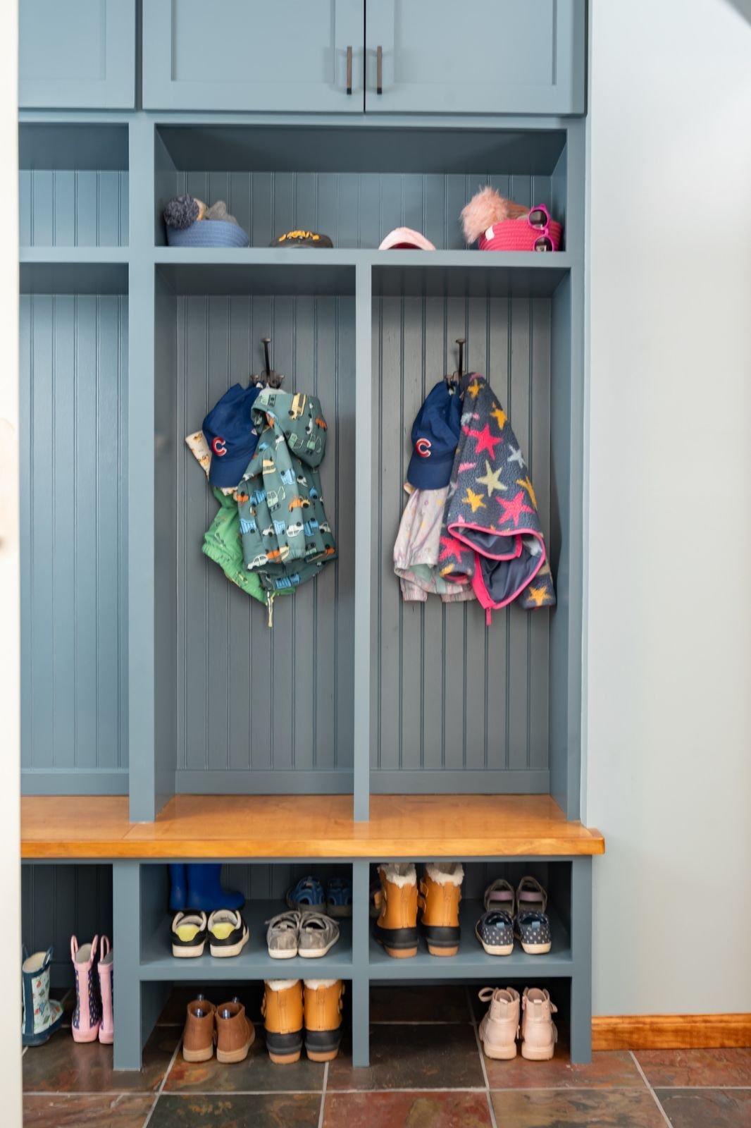 Organized blue built-in mudroom with shoe cubbies and hanging space located in Indiana