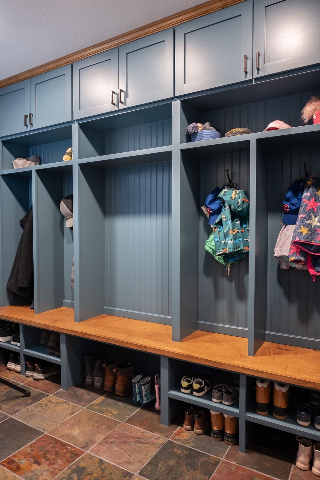Organized blue mudroom lockers with wood accents and shoe storage below located in Indian