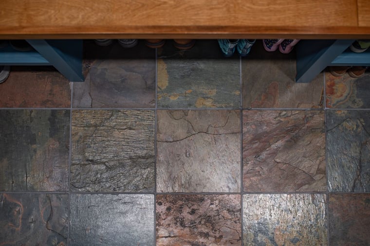 Slate tile floor with natural texture beneath built-in storage bench located in Granger, IN