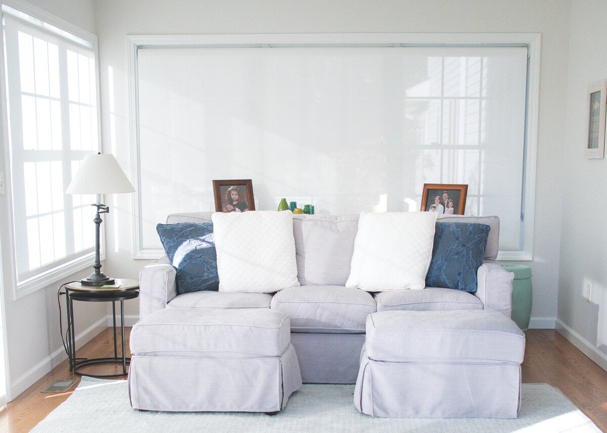 Gray sofa in sunroom addition near window with natural light by Peacock and Company