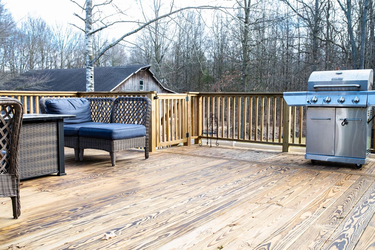 Grill and outdoor furniture on wood deck by Peacock and Company
