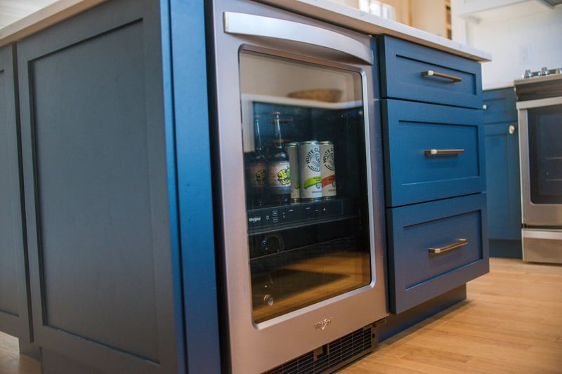 blue cabinets with bar fridge in kitchen island