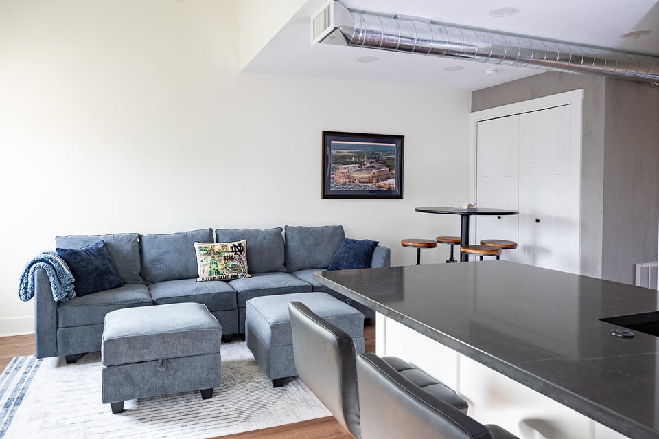 Couch in living space with kitchen counter and seating in view by Peacock & Company