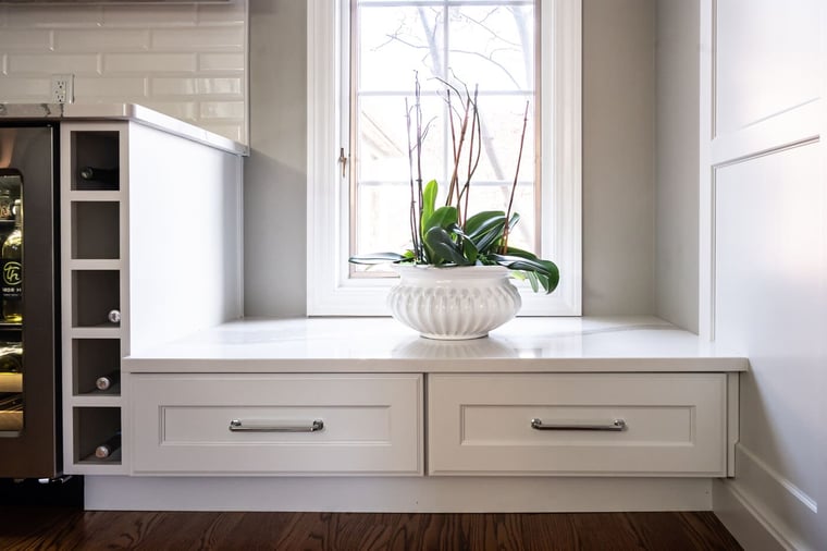 Lowered double white shaker cabinets beneath South Bend kitchen window with built-in wine holder 