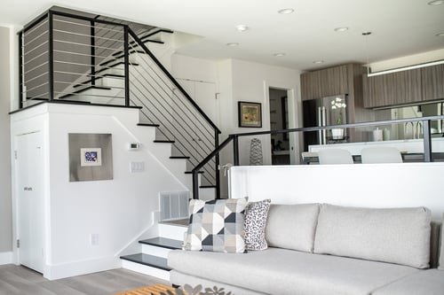 Modern living room with open staircase, sleek railings, and neutral seating in a South Haven, MI condo