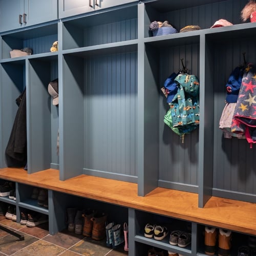 Organized blue mudroom lockers with wood accents and shoe storage below located in Indiana