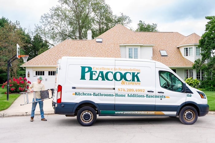 Peacock &amp; Company remodeling van parked in Harbor Country with a worker unloading a ladder in front of a large suburban home