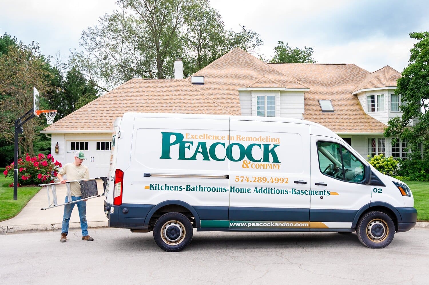 Peacock & Company remodeling van parked in Harbor Country with a worker unloading a ladder in front of a large suburban home