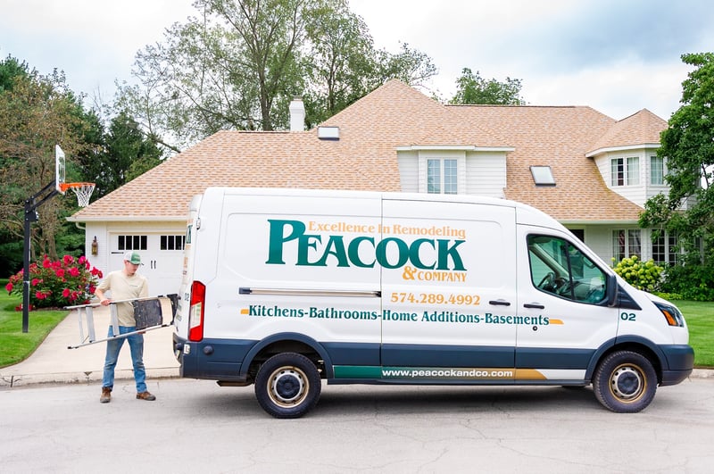 Peacock &amp; Company remodeling van parked in Harbor Country with a worker unloading a ladder in front of a large suburban home