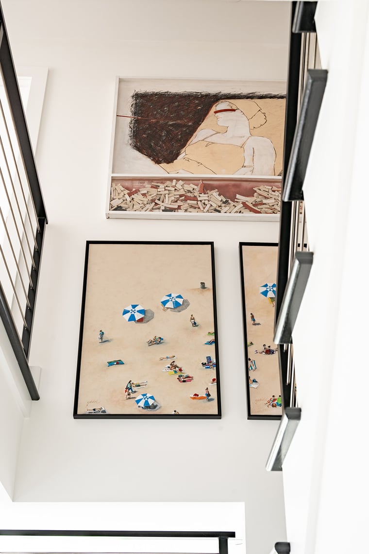 Stairwell gallery wall with framed artwork and black metal railings in a contemporary South Haven, MI interior