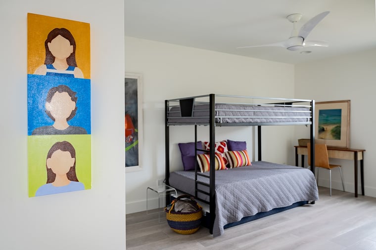 Modern bedroom with bunk bed, colorful artwork, and light wood floors in a South Haven, MI condo