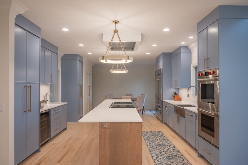 Island with blue cabinetry and stove top in South Bend, IN kitchen remodel by Peacock & Company