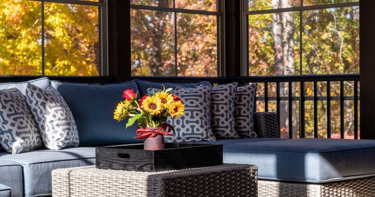 Screened-in porch interior with flowers on table in front of furniture
