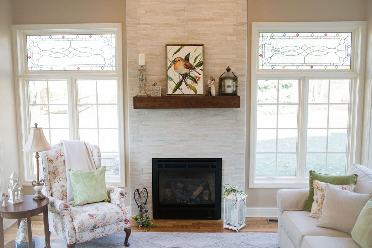 Sunroom addition interior with natural stone fireplace in between two windows by Peacock and Company